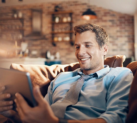 Man Relaxing On Sofa With Tablet