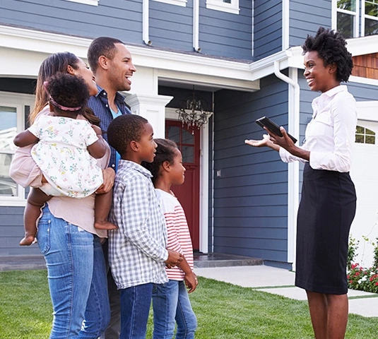 Real Estate Agent Greeting Family Outside Home