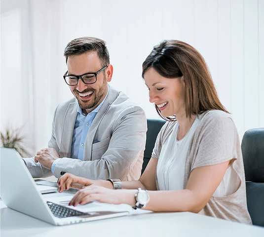Smiling Couple Working Together On Laptop